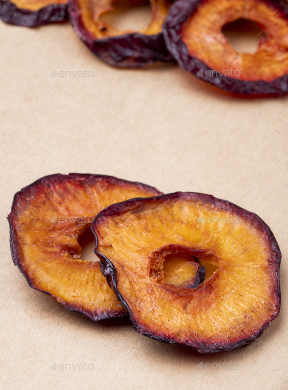 side view of dried plum slices isolated on brown paper texture